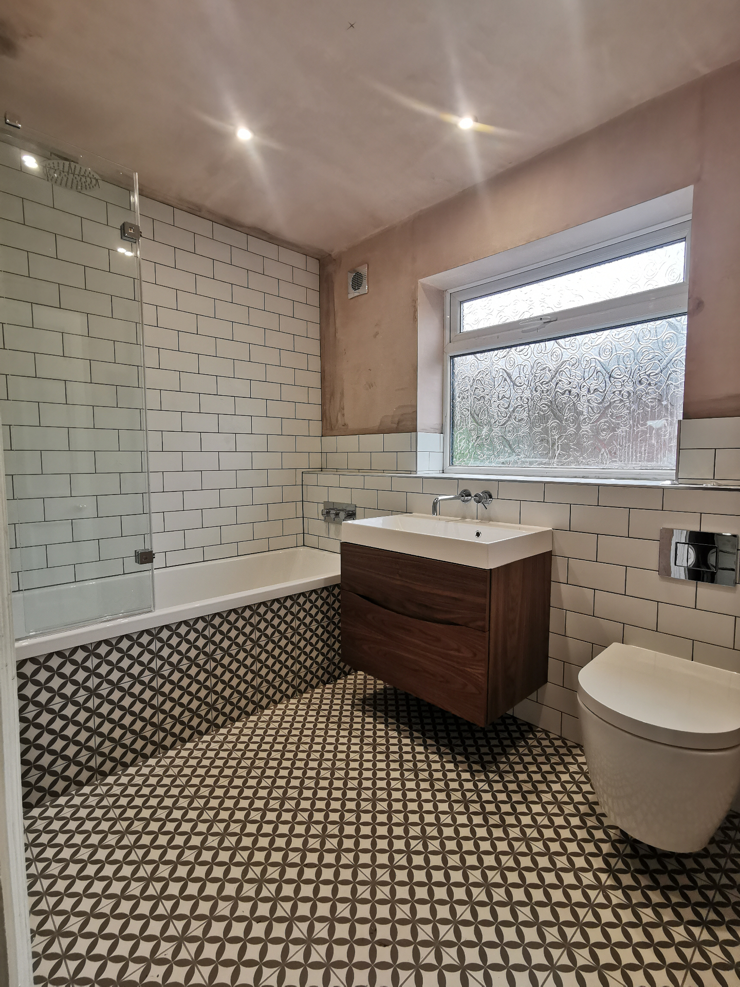 Patterned floor bathroom with wall-hung vanity and bath screen