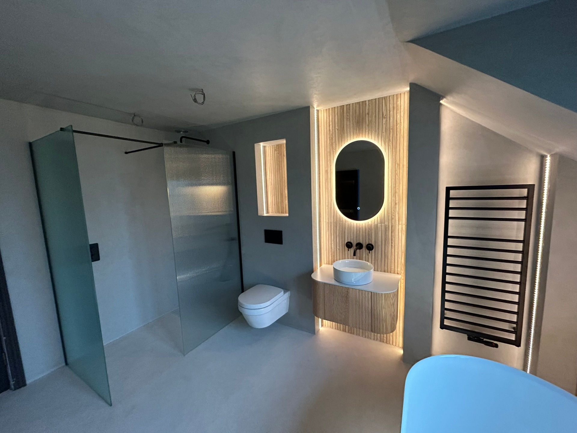Full microcement bathroom with glass shower screen and fluted vanity