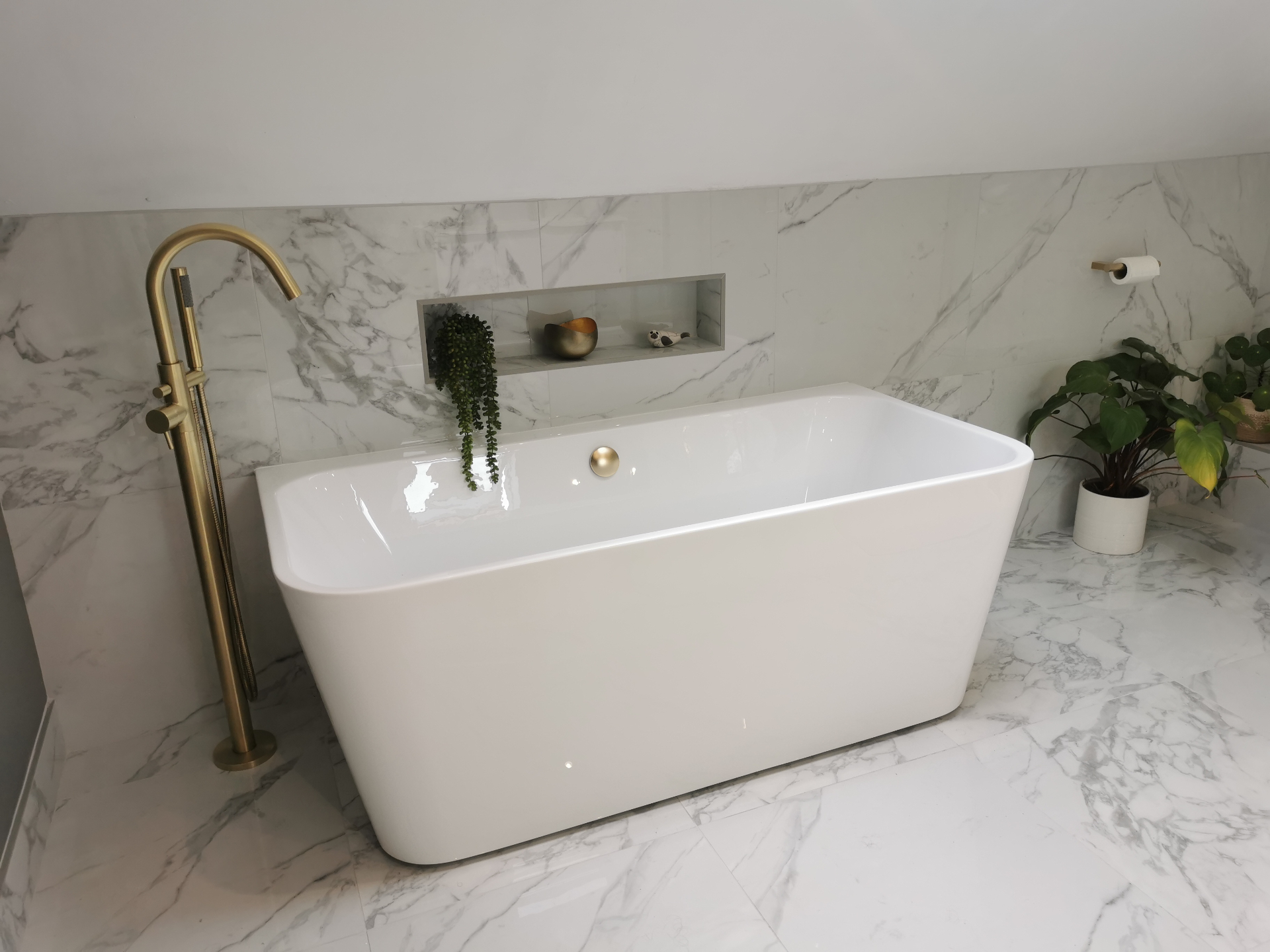 Freestanding bath with marble walls and brass floor filler