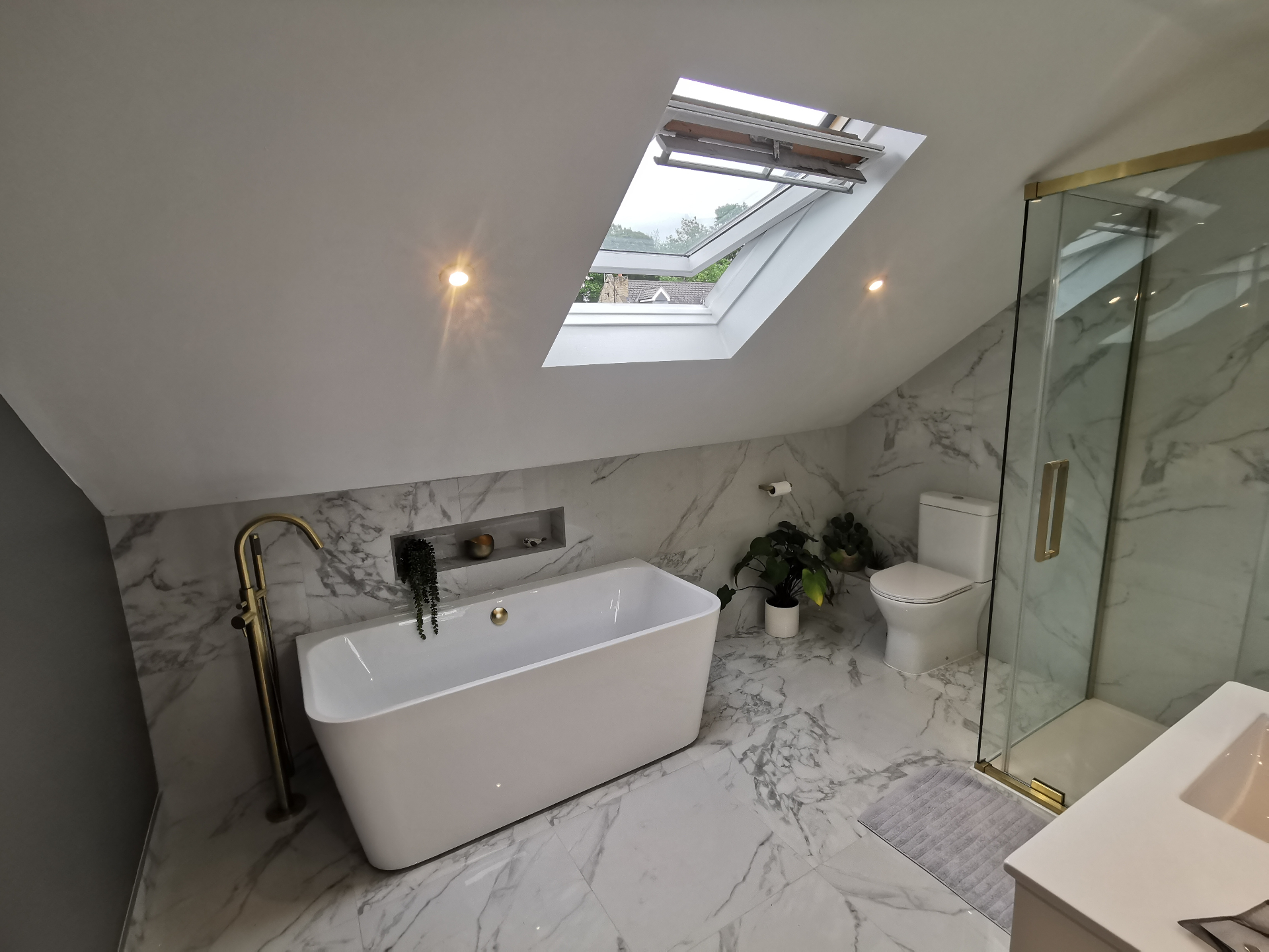 Wide view of marble bathroom with bath and shower