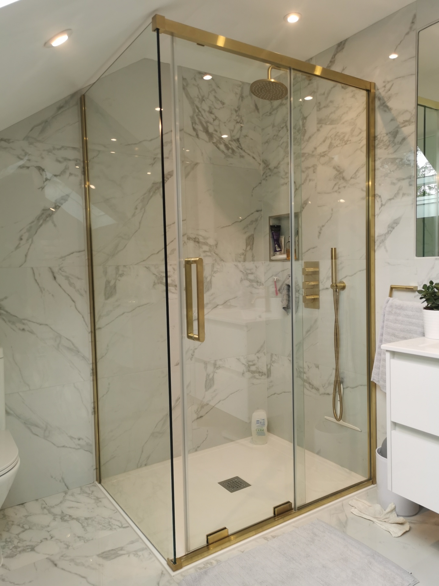 Frameless marble shower enclosure with brass details